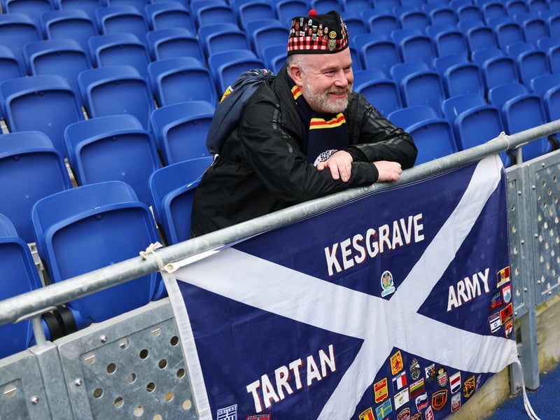 A Scotland fan poses for a photo in the stadium with his Tartan Army flag.