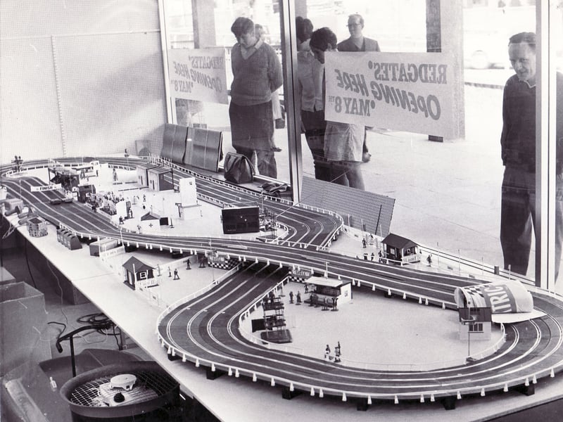 People stare through the window of Redgates toy shop, Sheffield, at a toy racing set in May 1968