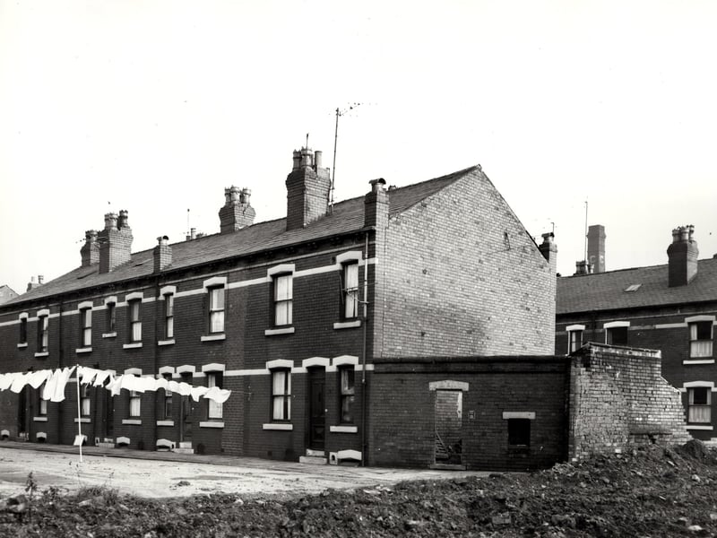 Even numbered back-to-back houses on Sheldon Street pictured in November 1966. Washing hangs across the street. Piles of rubble and earth can be seen in the foreground. Part of Nineveh Crescent is visible on the right edge.