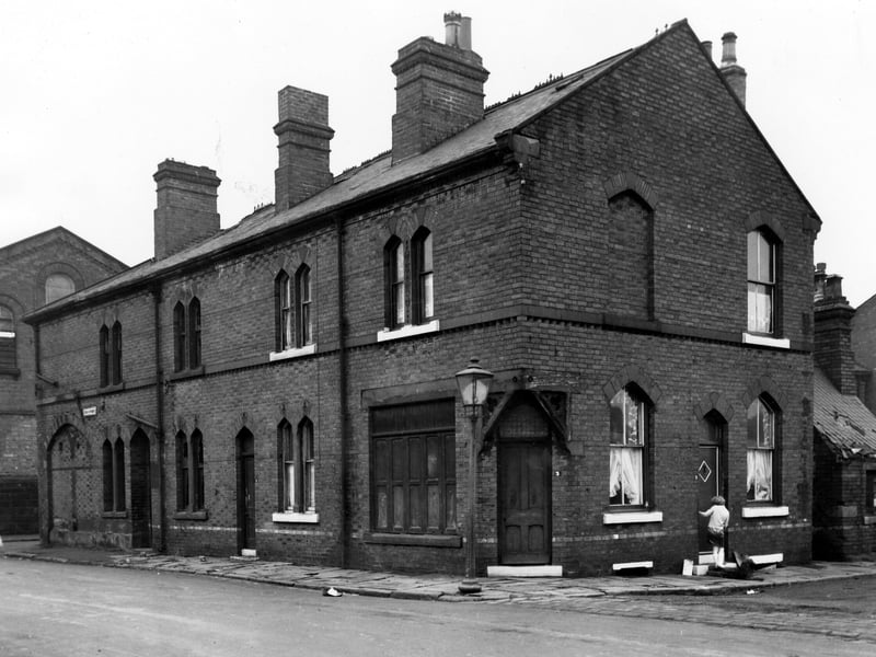 On the left the image in number 1 Czar Street with the entrance to number 3 at the corner with Bridge Court. This corner door and shop front style window on the left suggest that this was once a retail property. The entrance to the residential section of the property is on the right where a woman is stood by the doorstep with a dog at her feet. Pictured in November 1965.