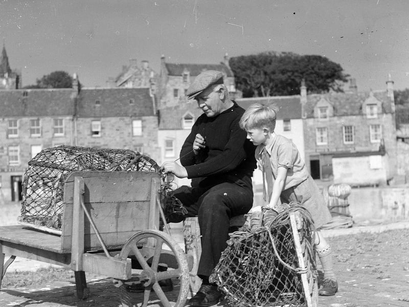 A young boy watches as a fisherman mends a lobster pot in Pittenweem in September 1950.