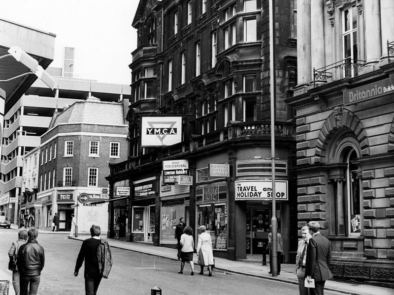 Shops on the east side of Albion Street, showing, from right, Britannia Building Society, then the YMCA building with shops including Hunting Lambert travel agents, Raymond Appleson opticians and Bentley films photograhic equipment, then beyond the junction with Albion Place is Dacre Son and Hartley, estate agents. In the background on the left the multi-storey carpark over Schofields.