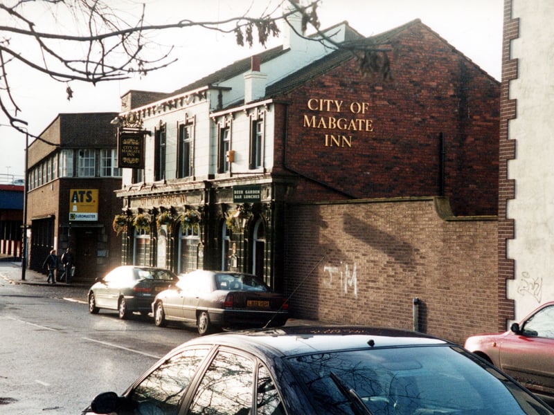 A view down Mabgate towards inner city ring road showing the City Of Mabgate Inn on the right. The Inn with its green tile facade dates C.1857 and has a cholera burial ground opposite. Hanging flower baskets decorate the exterior and a sign advertises a beer garden and bar lunches and that it is a Whitbread Inn.