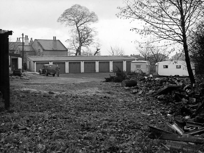 The premises of J.W. Atkinson, plumbers and electrical engineers, at number 590a Scott Hall Road. At the back of the yard is a row of seven garages, in front (on the right) are two caravans. To the left a man walks away from a parked van. Pictured in November 1950.