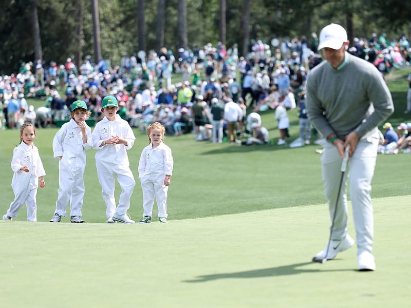 Poppy McIlroy, Franklin Fleetwood, Iris Lowry and Ivy Lowry watch as Rory McIlroy of Northern Ireland putts on the second hole during the Par Three Contest.