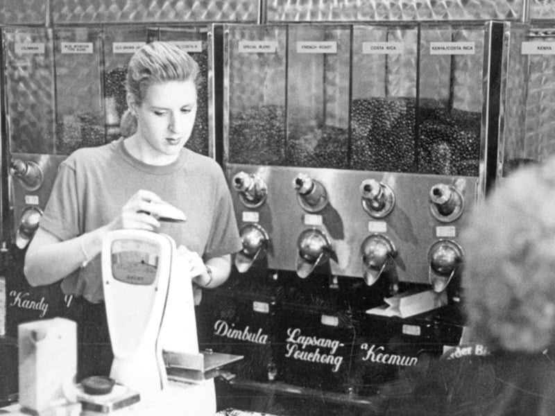 Weighing for a customer at P. and J. Pollard, tea and coffee dealers, Charles Street, Sheffield, in the 1980s, with coffee bean dispensers in the background