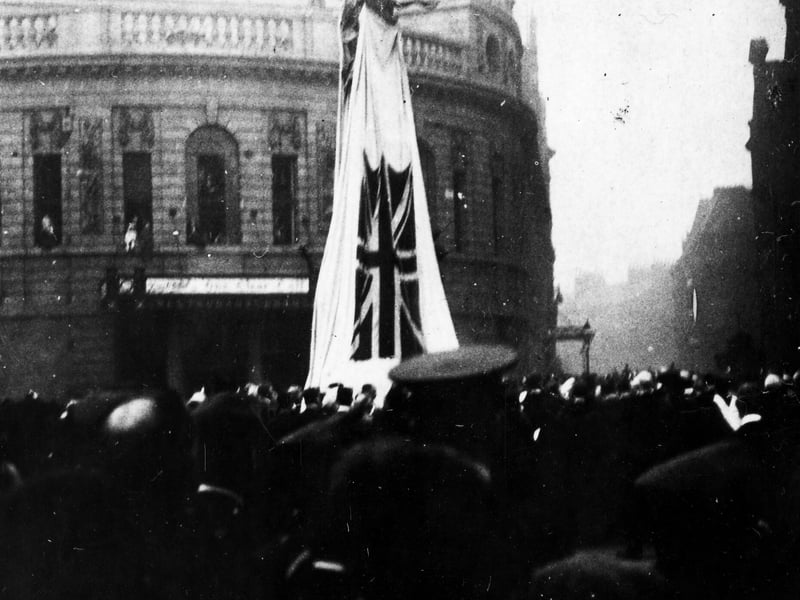 Dedication of the War Memorial in City Square in October 1922. The monument is in the centre draped with a covering which bears the Union Jack flag. The Majestic Cinema is in the background with Quebec Street to the right.