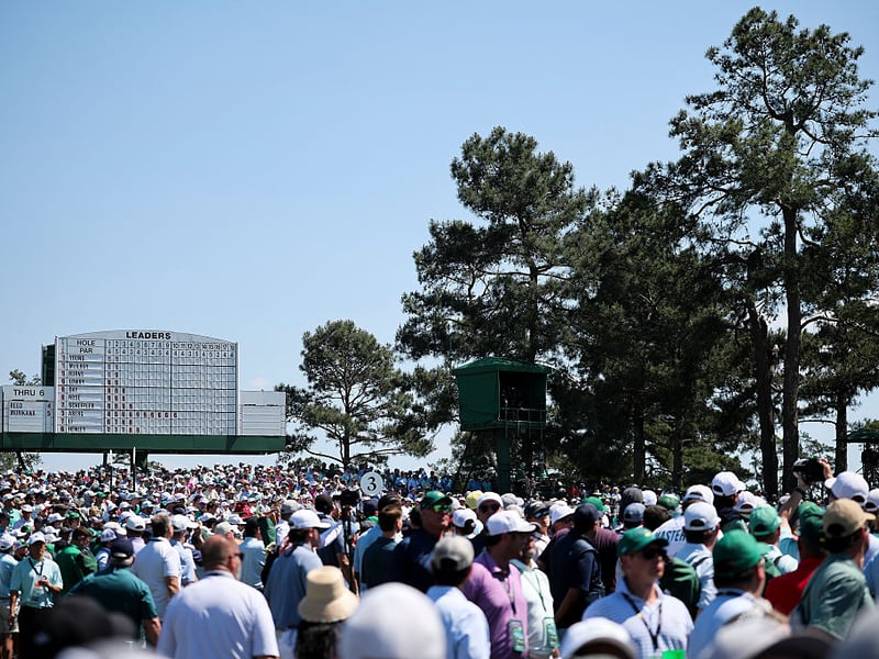 Crowds surround the leaderboard on the third hole.