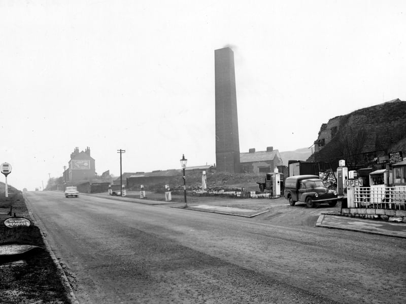 A view looking south west along Gelderd Road in November 1952. In the foreground is Ravel's filling station owned by W.H. Carr with Ravel's Coal Mine just behind. The garage has petrol pumps and a van and lorry parked in it. The mine has a tall square chimney. In the distance is a house with an Esso advertisement on the side.