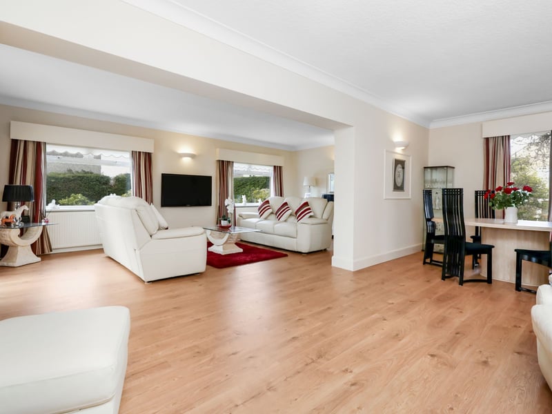 The large family/dining room flows seamlessly through to the living room with two picture windows overlooking the manicured garden.
