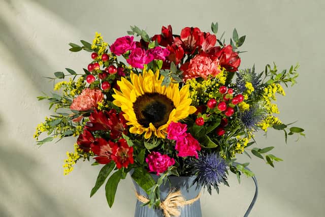 Bunches’ Golden Woodland bouquet features a bold sunflower with rich red, pink and yellow blooms for a vibrant autumn display.