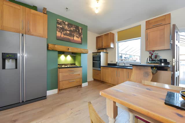 A solid oak fitted kitchen combines black granite worktops with an integrated oven and range hob
