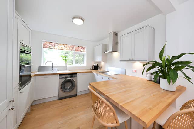 Dove-grey Howdens units, ample worktop space and a large island with breakfast bar give the separate kitchen a practical and contemporary feel