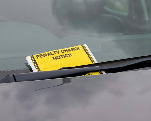 A penalty charge notice parking fine attached to car windscreen