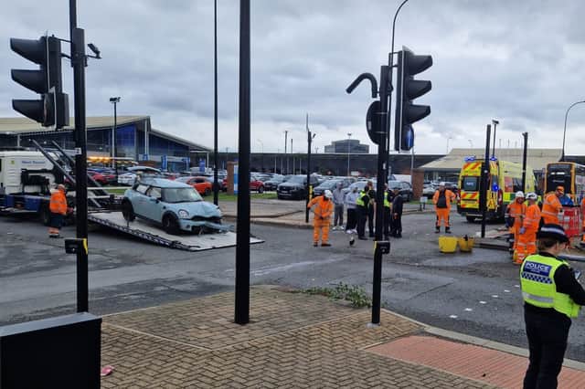 Road workers sweep up as a car is winched on to a low loader on Savile Street.
