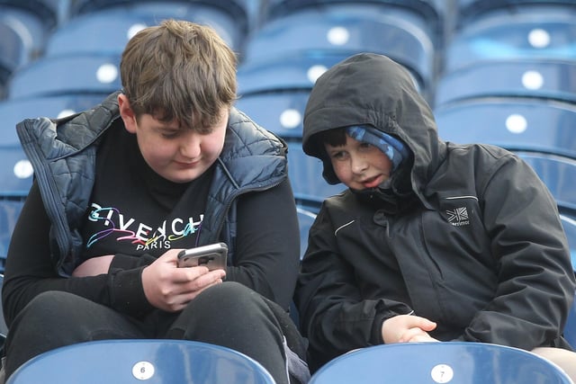 Two North End fans have a look at one of their phones to kill a bit of time before the Championship match.