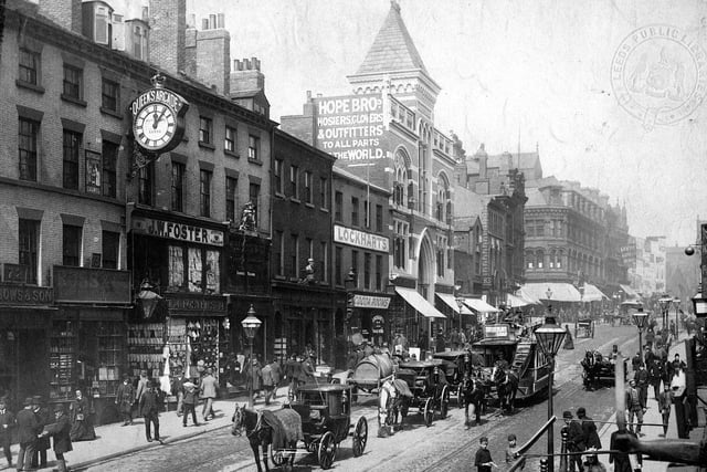 Shops on the west side of Briggate looking in the direction of The Headrow. The pavements are crowded with shoppers and the street is busy with horse trams and carts