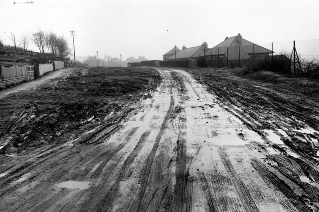 Looking south along Blue Hill Lane from near the junction with Tong Road. The picture shows the unmade, muddy surface with tyre tracks.