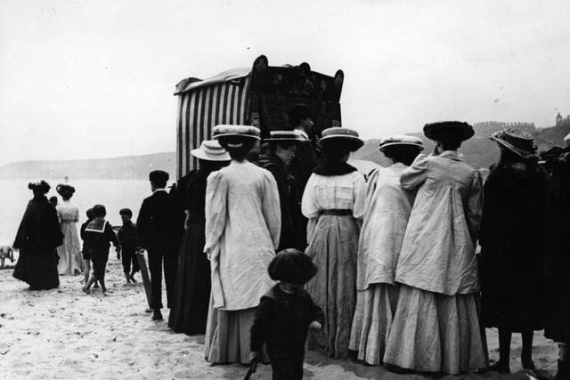 In June 1908 crowds gather to watch a Punch and Judy puppet show on the beach.