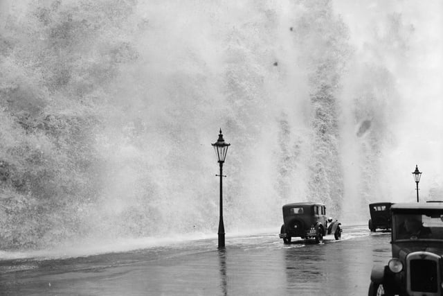 A giant wave dwarfs a car on the seafront on August 8 1931.