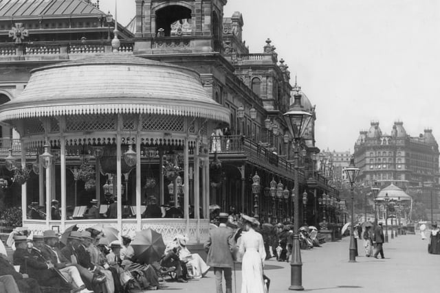 Victorians with parasols enjoy a walk along the promenade in front of the Spa, past a bandstand in 1900.