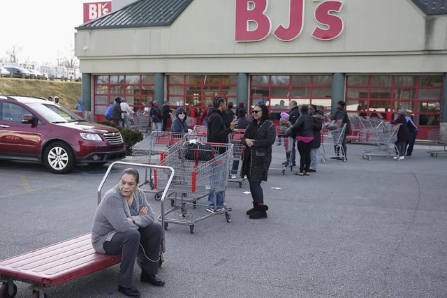 Jacqueline Moss-Holland sits on a cart as hundreds of shoppers line up to enter a BJ's Wholesale Club in Springfield, Philadelphia.