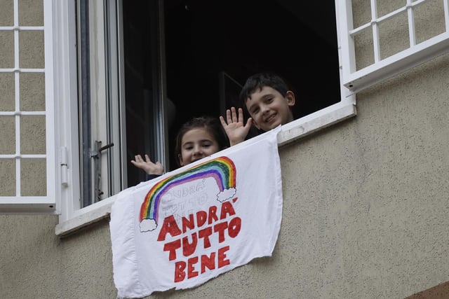 Francesco and Greta Innominati wave after placing a banner reading "Everything is gone be all right" out of a window of their apartment in Rome.
