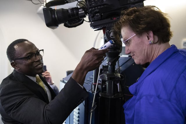 A member of the media, right, gets their temperature taken by member of the White House physicians office.