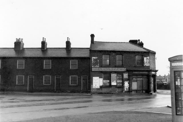 Grocer's shop. G H Moon and Son at the tend of terraced houses on Cross Gates Lane with its junction with Station Road. The shop has advertisement posters for Galista Tent Wine, Lyons tea and Marmite.
