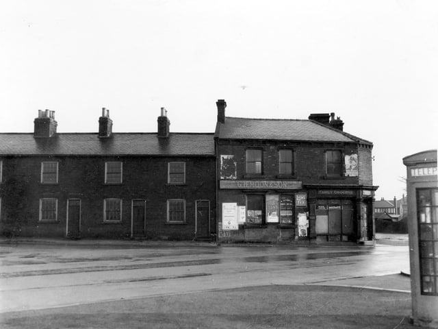 Grocer's shop. G H Moon and Son at the tend of terraced houses on Cross Gates Lane with its junction with Station Road. The shop has advertisement posters for Galista Tent Wine, Lyons tea and Marmite.