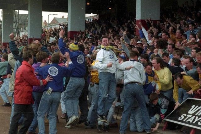 Leeds fans celebrate in the away end at Bramall Lane.