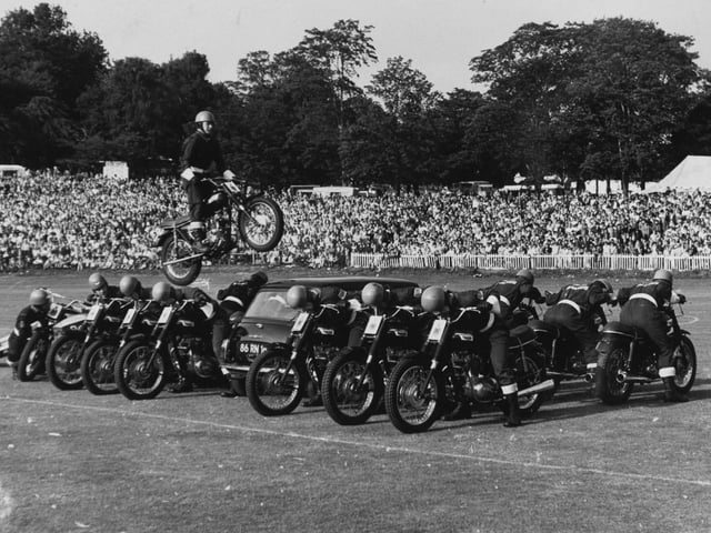 A member of the Rotal Marines Motor-cycle Display Team performs a spectacular leap over 14 men and a mini car at Leeds Gala in August 1972.