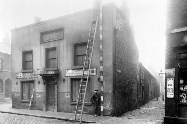 Boarded up 18 Bridge Road in Holbeck, later demolished. Advertisements on the shopfront for 'Samuel Smith's Old Brewery Tadcaster' . To the left is an alleyway leading down to Front Walk.