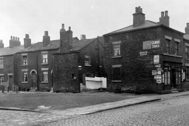 A small boy to left looks at the photographer on Czar Street in Holbeck. Terraced housing runs all the way along Front Walk. A shop is no 1 Front Walk owned by Mrs Jane Ann Burns. Sheets are hung outside a house on Bridge Road.