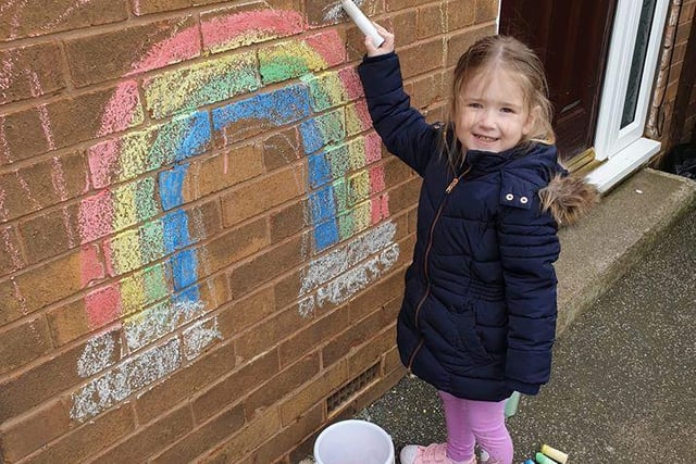 Little Mia drew a rainbow in chalk on the side of her house