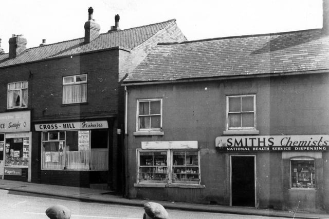 Cross Hills showing shops and businesses. Far left is a grocery store with ads in window for Daz & Birdseye. Also advertised are various tobacco brands. To the right of the grocer's is Cross Hill Fisheries and then Smith's Chemists