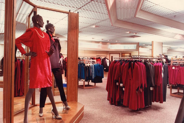 The ladies' fashion department. Two mannequins display fashions of the day, typical of the early 1980s featuring batwing sleeves and exaggerated shoulder pads. Ladies' winter coats and suits are also visible.