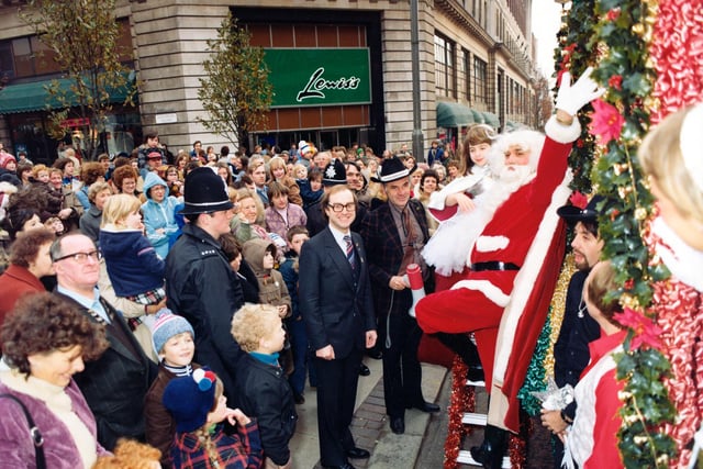 June 1980 and crowds of people line The Headrow and the corner of Lewis's for the 7th Annual Lord Mayor's Parade. Santa waves to the crowds and man seen centrally with spectacles is Lewis's general manager Steven Arundel.