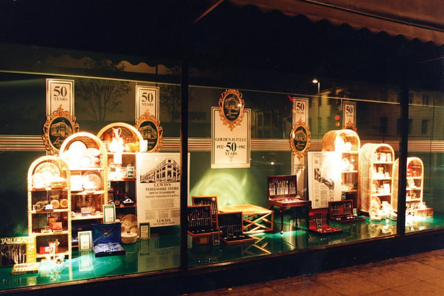 A window display in Lewis's marking 50 years of trading in September 1982. Arched cane display units show off dinnerware and glassware, and there are presentation canteens of cutlery.