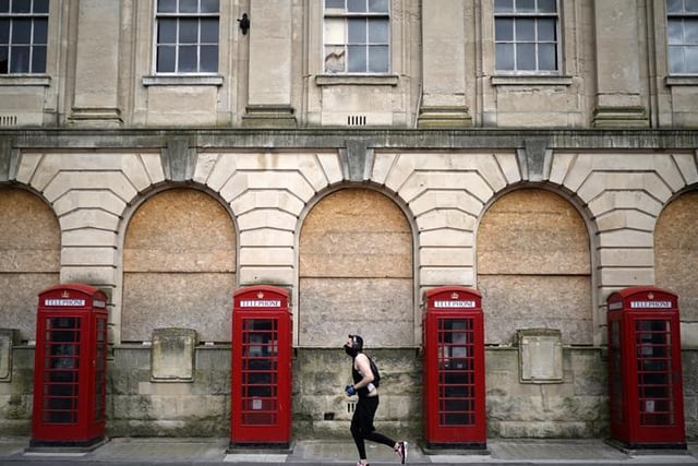 A man wearing a mask jogs past red phone boxes in Blackpool town centre (Photo by Christopher Furlong/Getty Images)