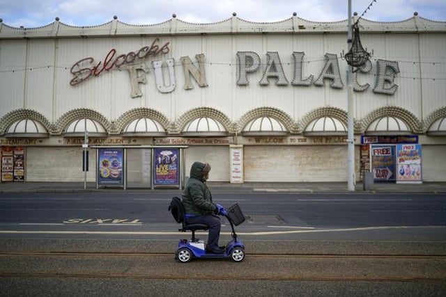 A person on a mobility scooter passes some attractions on Blackpool's Golden Mile (Photo by Christopher Furlong/Getty Images)