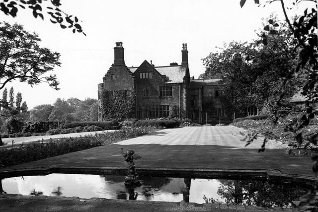 Carr Manor on Stonegate Road. A pond with a cherub fountain statue is in front of a long lawn.
