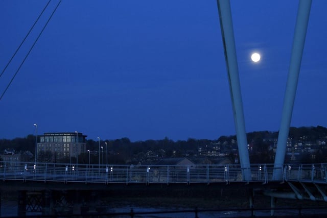 The moon castings its unearthly glow over the Lune Millennium Bridge in Lancaster