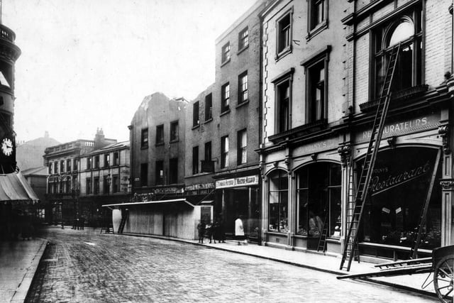 Bond Street looking east to Commercial Street. Powolny's restaurant is on the right. A window cleaning cart is on the street with a ladder leaning up against the building.