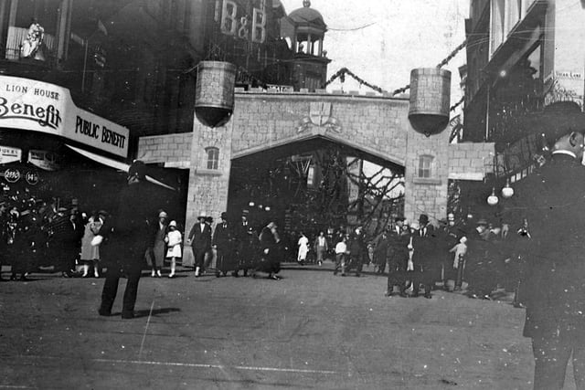 Kirkgate during the Leeds Tercentenary in 1926. A medieval castle arch has been put up for the occasion. On the left is the junction with New Market Street, with the Public Benefit Boot Co. Ltd. On the corner, and on the right is the junction with Vicar Lane.