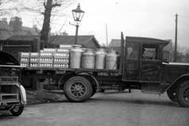 A milk delivery wagon belonging to the firm of J. Harvey & Son of 37 Reginald Street. The vehicle is loaded with large milk churns and crates containing pints of milk.
