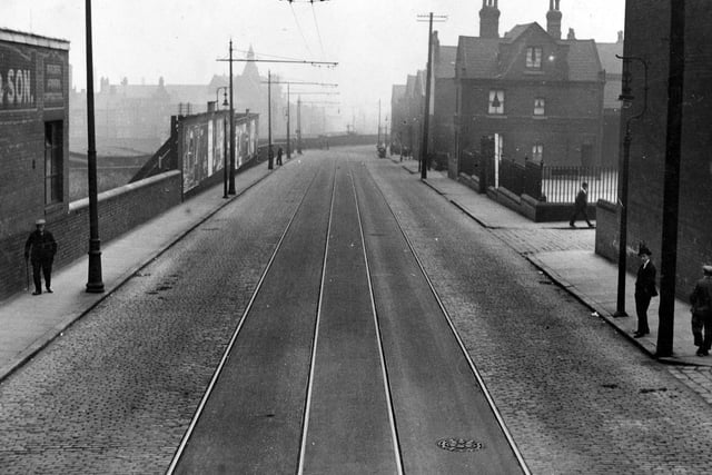 Armley Road in the direction of Wellington Bridge. On the left edge is part of the premises of John Wilby and son, builders and monumental masons. On the right, the fence around the yard of Castleton County Primary School is visible.