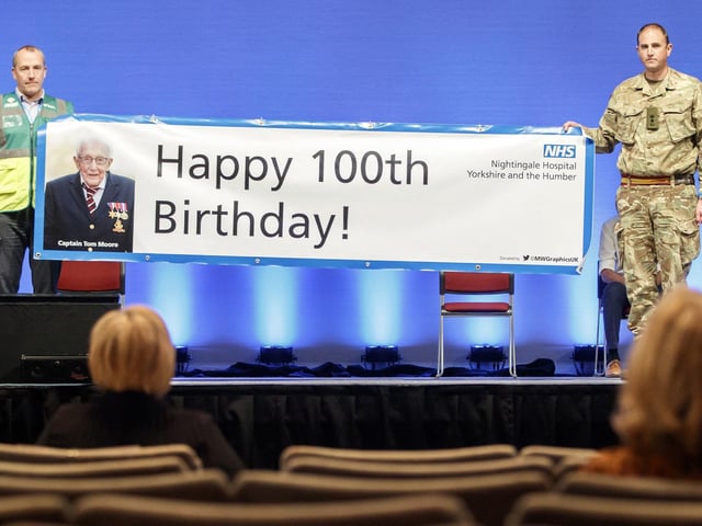 Guests hold up a sign wishing a Happy 100th Birthday to Captain Tom Moore as he and his daughter Hannah Ingram-Moore speak via videolink at the opening of NHS Nightingale Hospital Yorkshire and Humber in Harrogate.