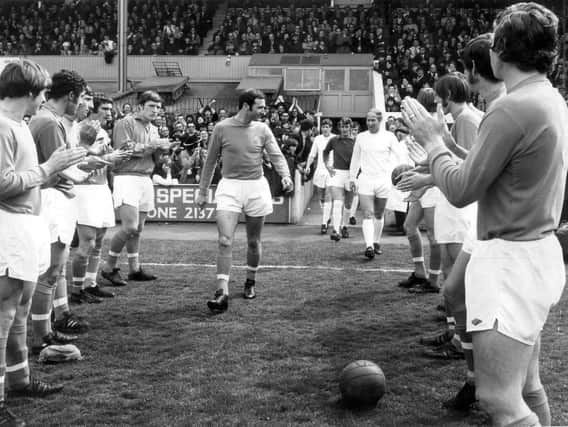 Jimmy Armfield walks to the pitch for his final game flanked by Manchester United players.