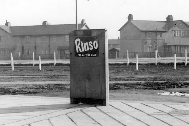 Tramlines on Middleton Park Road with houses in the background. The main focus of the photograph is a rectangular object (possibly a tram timetable) which has an advertisement for Rinso on the back.